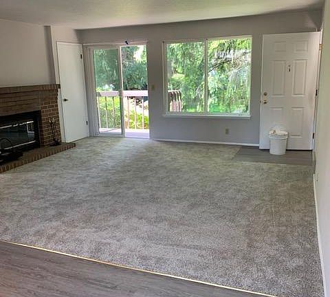 Living room as viewed from dining room. It shows the deck on left and large window looking over back yard. Fireplace is on the south wall of the living room. All new carpet and flooring in kitchen and dining area. Living room measures 15 x 16