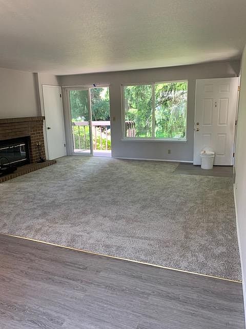 Living room as viewed from dining room. It shows the deck on left and large window looking over back yard. Fireplace is on the south wall of the living room. All new carpet and flooring in kitchen and dining area. Living room measures 15 x 16
