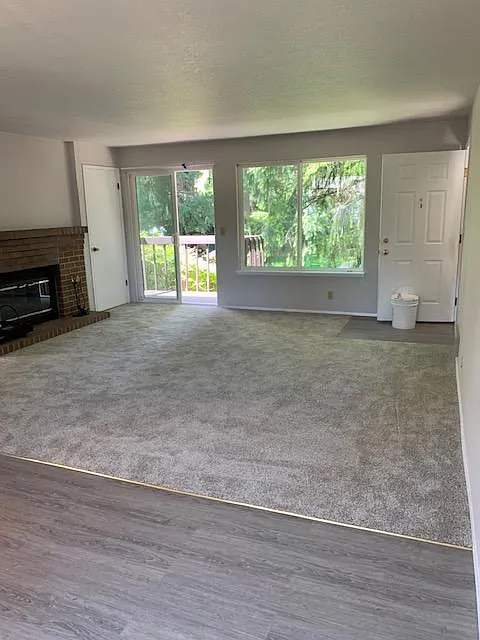 Living room as viewed from dining room. It shows the deck on left and large window looking over back yard. Fireplace is on the south wall of the living room. All new carpet and flooring in kitchen and dining area. Living room measures 15 x 16