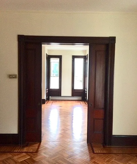 Living room looking into primary bedroom with pocket doors