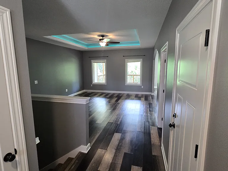 Living Room from Front Door (Garage and first floor Laundry doors on right and closet and stairs to Basement on the left). Multi color lighting in tray ceiling.
