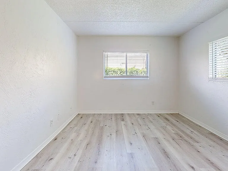Bright and airy room with large windows, showcasing elegant light wood flooring and fresh white walls, perfect for a cozy living space.