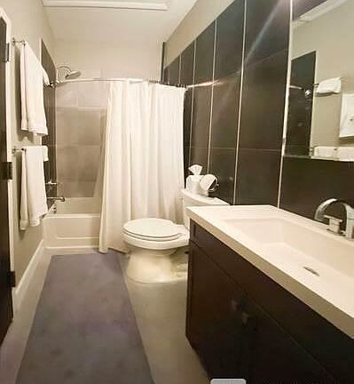 Full bath with tile accent wall and laundry closet, rain shower head