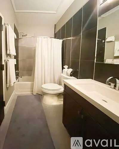 Full bath with tile accent wall and laundry closet, rain shower head