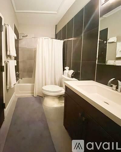 Full bath with tile accent wall and laundry closet, rain shower head