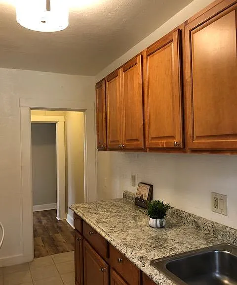 Kitchen has wood cabinetry, laminate counter top, gas stove, dishwasher, garbage disposal, 10 cubic foot refrigerator, tile flooring