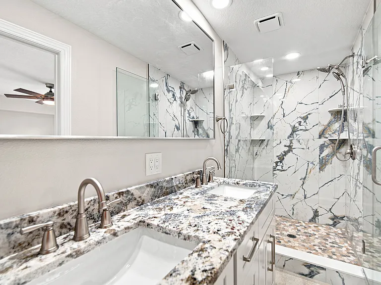 Primary bathroom with two sinks and walk in glass paneled shower