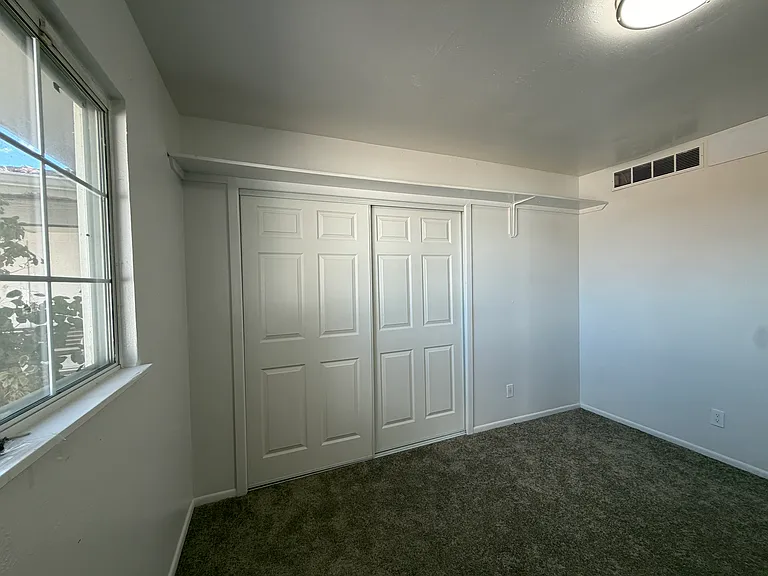 Bedroom 1 features a built-in shelf, a spacious closet, updated carpeting, modern light fixtures, and upgraded electrical outlets, offering both comfort and functionality.