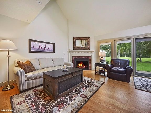 The living room features a cathedral ceiling, engineered hardwood floors, a gas fireplace with a cus