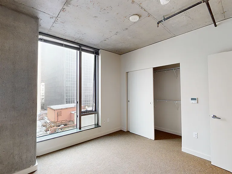 Spacious apartment bedroom with plush carpet flooring.