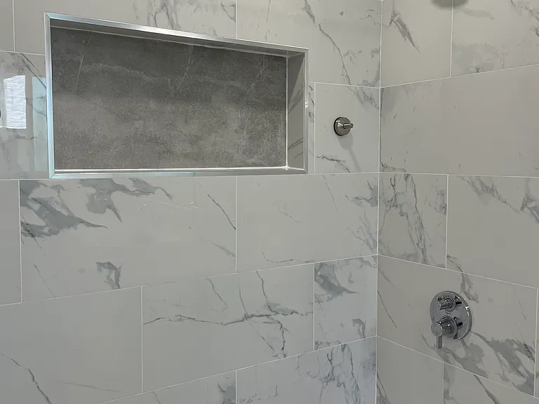 Brand new shower/tub with porcelain tile, niche, and fixtures.
