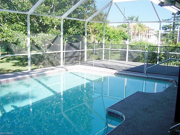 View of pool looking towards canal and reflection of tree in the crystal clear water.   Note Baby security fence and a large are