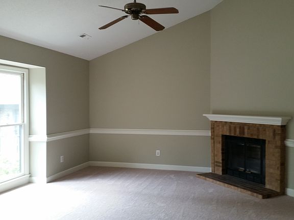 Living room has fireplace, ceiling fan and large window
