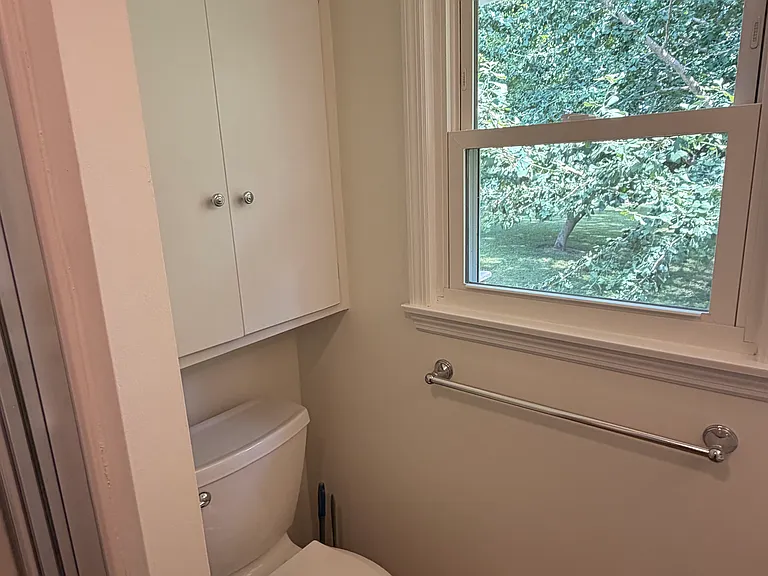smaller bathroom with storage above toilet