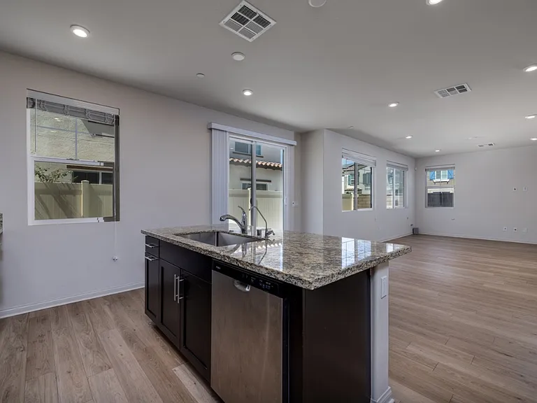 Open-concept kitchen with laminate flooring, island granite countertop, and direct access to the garage and backyard. Overlooks the spacious living area, creating a perfect flow for entertaining and everyday family living.