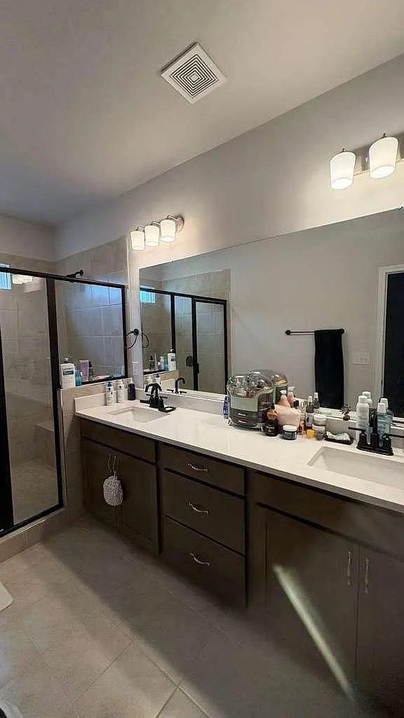 Room 2 bathroom with a long double-sink vanity, oversized mirror, and a glass-enclosed shower for everyday convenience. - Coulee Ln