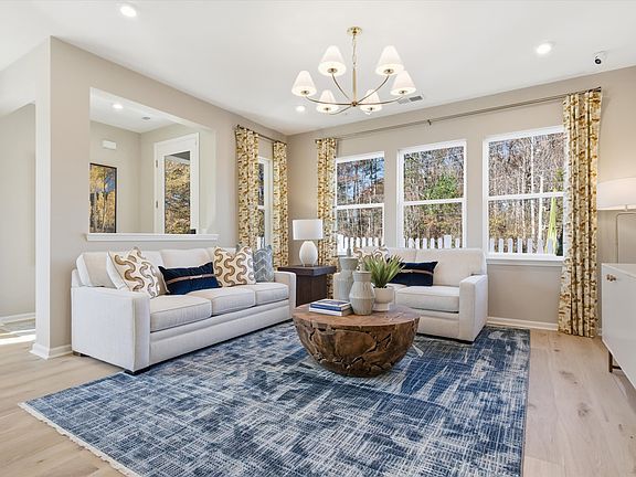 A cozy and well-furnished living room with a plush sofa, armchairs, a patterned rug, and a chandelie