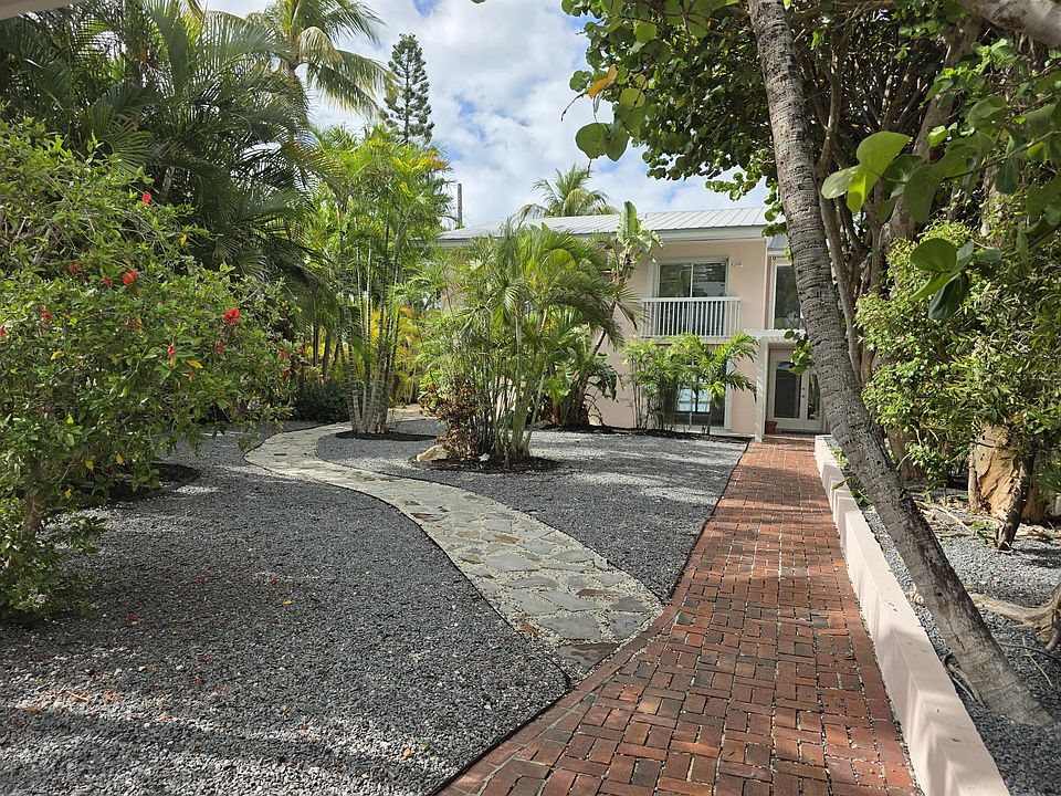 Gated entrance view. Red bricked path leads to front door atrium entrance. Slated path yields left towards waterfront deck, dock and to garden exterior access stairs to upstairs balcony