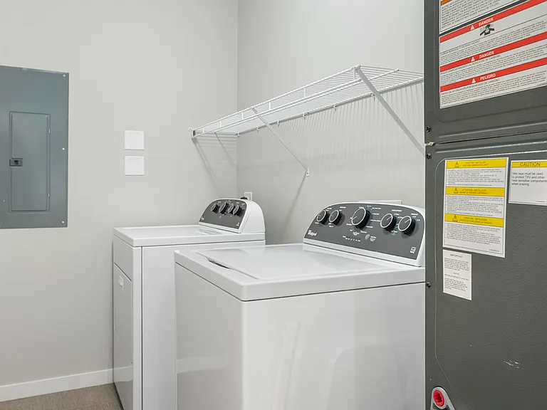 Modern laundry room featuring energy-efficient washer and dryer, ample shelving, and contemporary design. Modern laundry room featuring energy-efficient washer and dryer, ample shelving, and contemporary design.