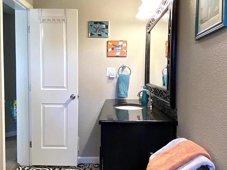 Main level master connected full bathroom with granite countertop, designer tile shower and floors, and toilet.