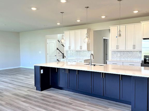 Island kitchen and open family room in a DRB Homes Emory II plan at the Tinker s Preserve community.