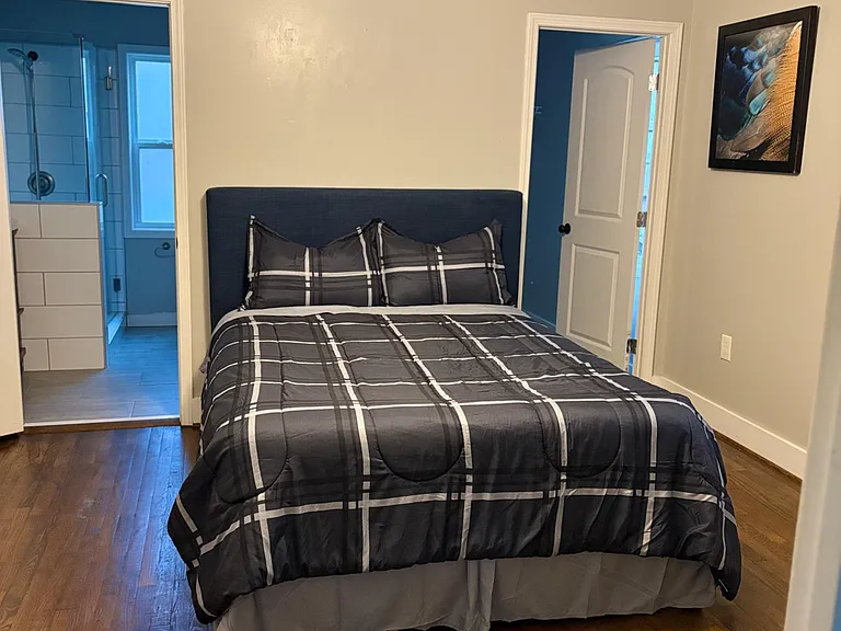 Furnished bedroom with hardwood floors, ceiling fan, and 55" tv mounted