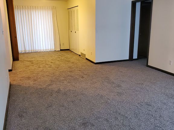 second view from living room with entry and kitchen on left, sliding door to rear, and hallway to common bathroom and bedroom on right