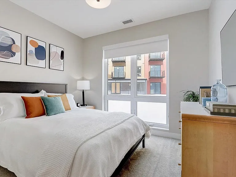 Bedroom with floor to ceiling windows that feature blackout rolling shades and walk-in closet