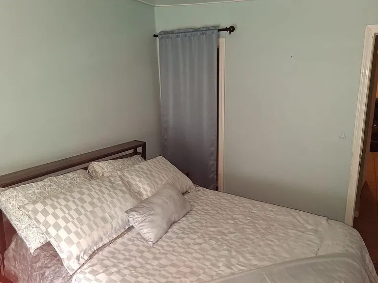 Furnished bedroom with a full bed, neutral walls, and a window with curtains for privacy and light control.