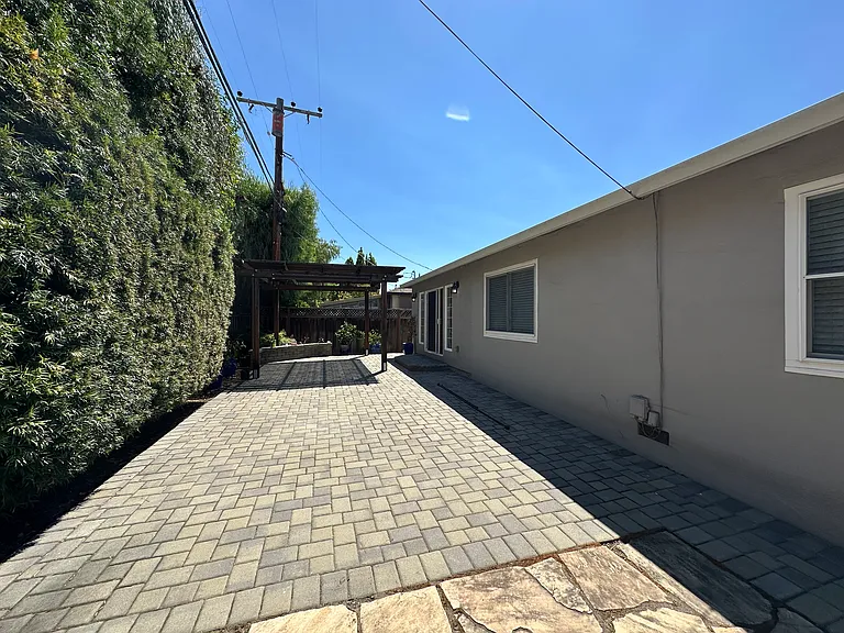 Fenced in yard with pavers and pergola