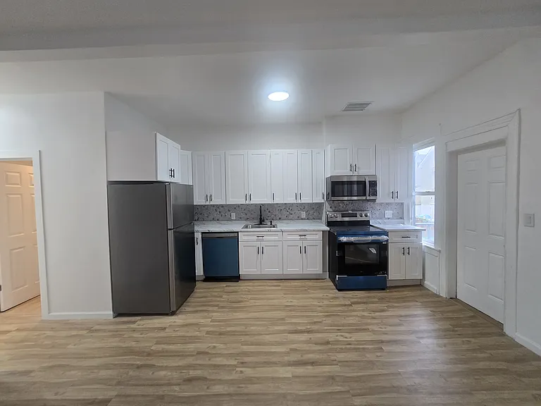 Renovated kitchen with stainless steel appliances including dishwasher, microwave, fridge and stove.