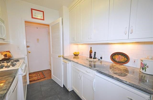 Renovated kitchen with custom cabinets, granite counters and appliances including a dishwasher, microwave, range, refrigerator and separate freezer.