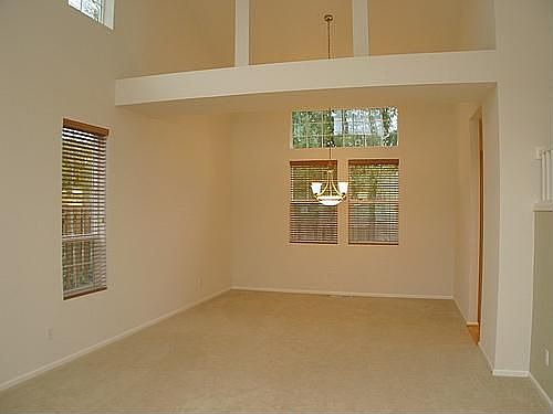 Living rm and dining rm with soaring vaulted ceilings and custom blinds