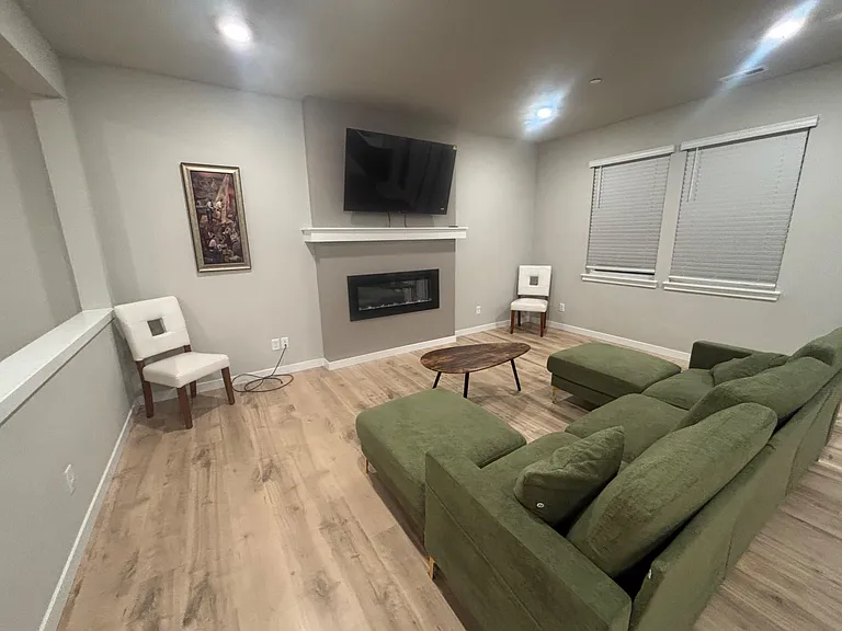 Living room with wood-look flooring, a wall-mounted TV, and a fireplace feature wall with seating space.