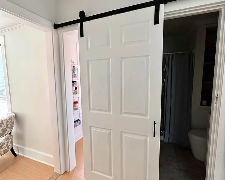 This barn door leads to the bathroom. To the left of the bath is the walk-in pantry.
