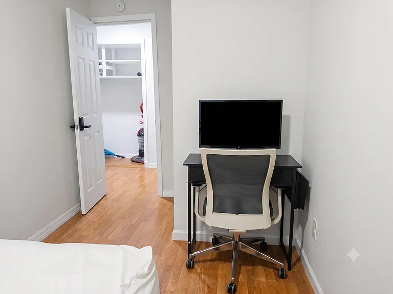Bedroom includes a dedicated desk workspace with TV and laminate flooring, plus easy access to the hallway.