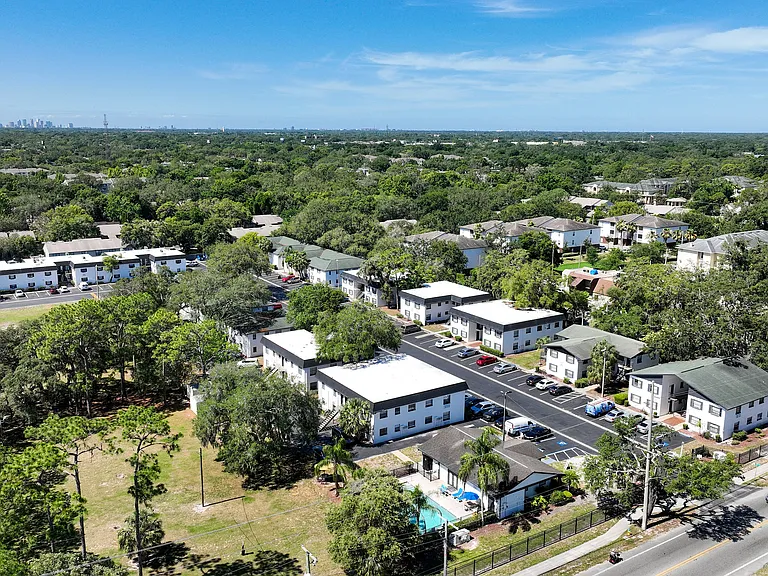 Charming suburban apartment complex surrounded by lush greenery, offering modern living with a pool and ample parking.