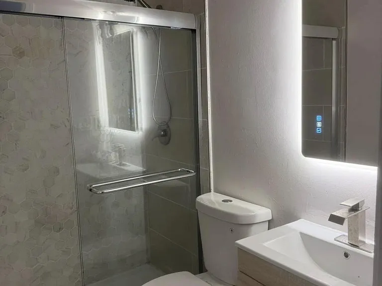Updated bathroom with glass-enclosed shower, modern vanity, and illuminated mirror for comfortable daily routines.