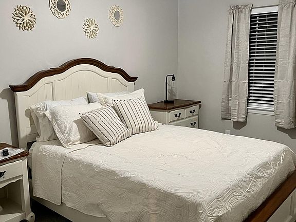 Queen bedroom with dresser and nightstand along with smart tv