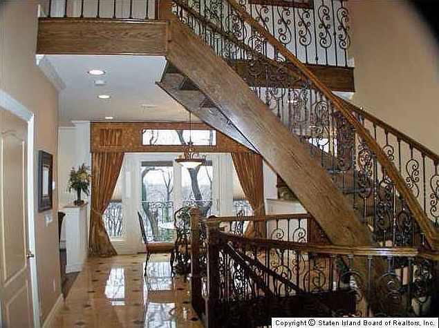 Two Story Entry With Floating Oak Stairs and Decorative Wrought Iron  Work