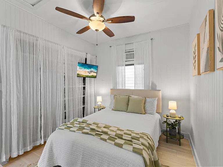 Back bedroom with double bed, AC, ceiling fan, dresser, side tables and large closet with built-in shelving.