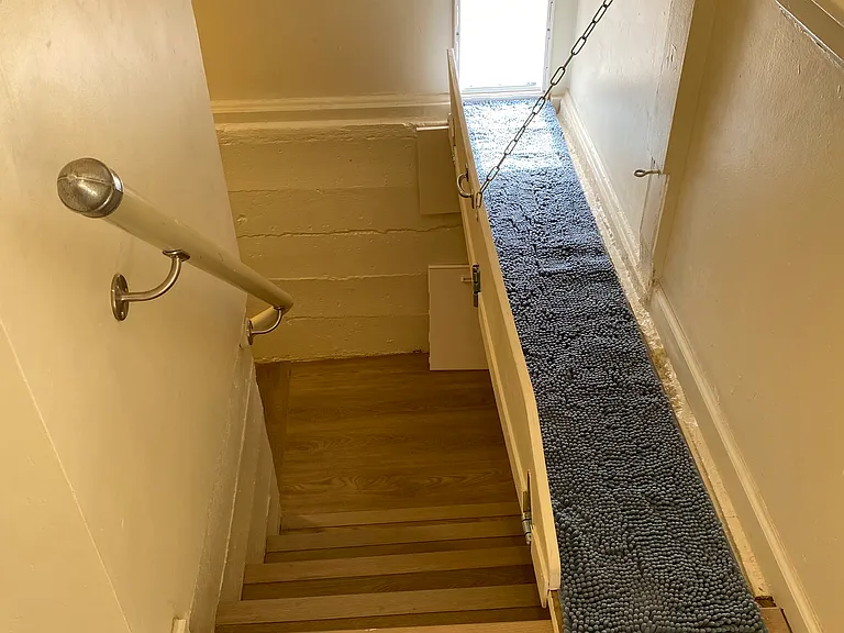 Stairs to basement and laundry room with dog walkway to dog door and separate dog yard.