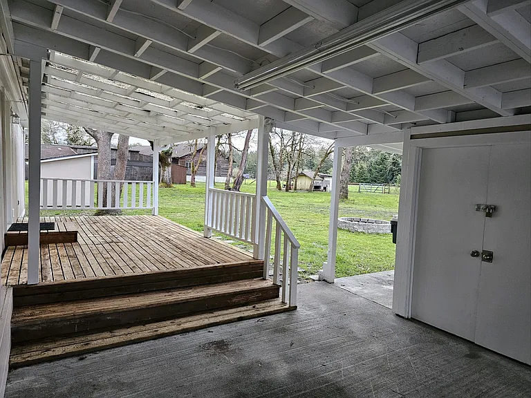 Carport, shop entry door, and deck seating area off the back door entrance