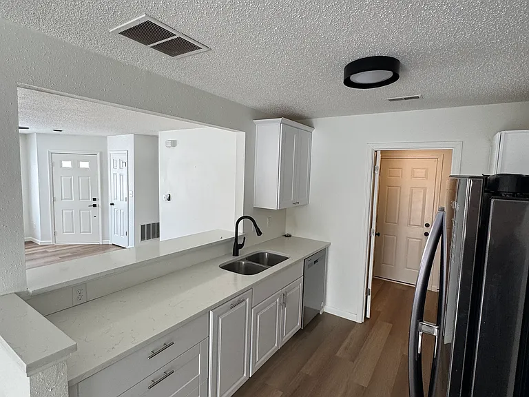 Modern kitchen with stainless steel refrigerator, ample counter space, and double basin sink.