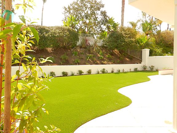 Large backyard with new landscaping including artificial grass.