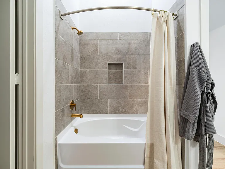 Primary bath with a tiled tub and shower surround, built-in niche, and warm-toned finishes designed for everyday comfort.