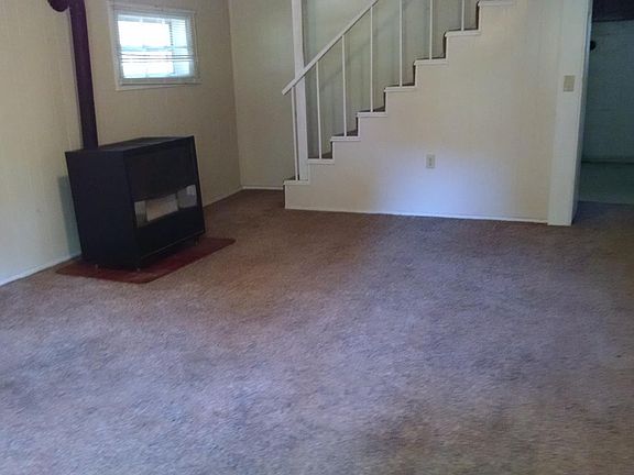 Living room showing gas heater and stairs going up to 2 bedrooms