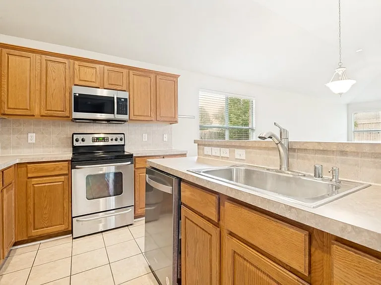 Stainless steel appliances including a refrigerator and oversized sink.