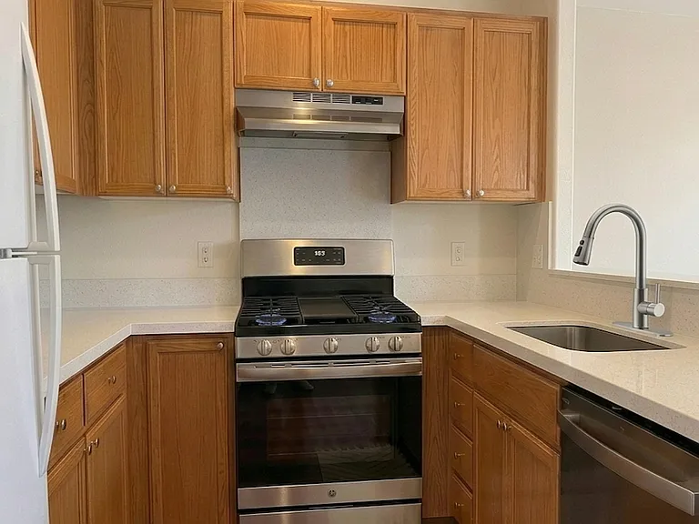 Kitchen with refrigerator, stove/range, dishwasher, and upgraded countertop.
