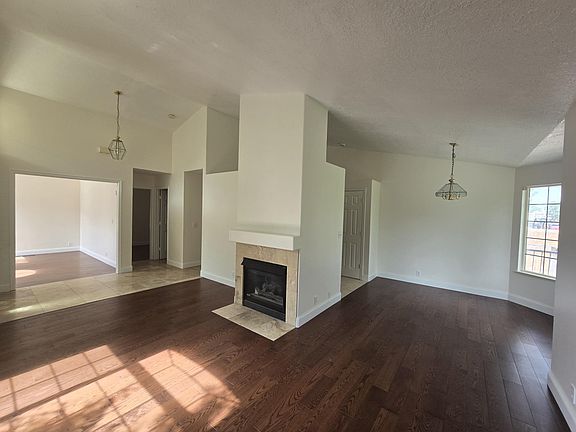 Living room with fireplace and solid oak floors. Kitchen is to the right, the entry, den, and bedroom is to the left